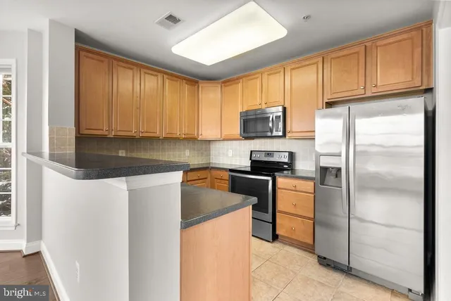 a kitchen with stainless steel appliances granite countertop a refrigerator stove microwave sink and cabinets