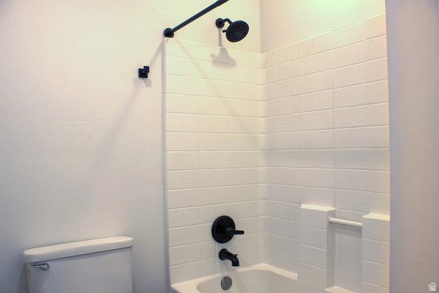 1115 North Main Street Bountiful, UT 84010 - Photo 4 of 17 Bathtub and shower combination featuring white tiled walls, matte black shower fixtures, an integrated soap dish, and a white porcelain toilet