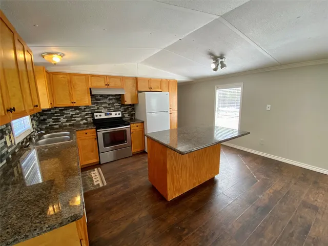 an open kitchen with wooden floor and stainless steel appliances