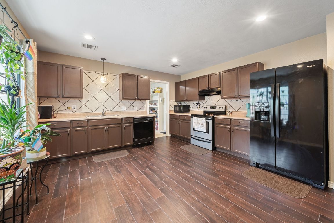 a kitchen with stainless steel appliances kitchen island granite countertop a stove a sink and a refrigerator