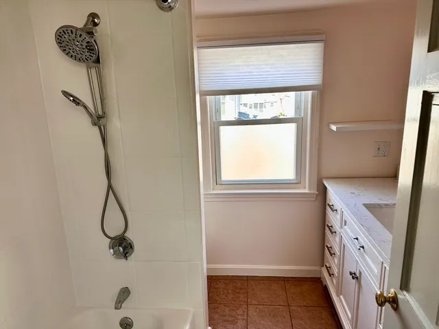 a bathroom with a granite countertop sink a window and a shower