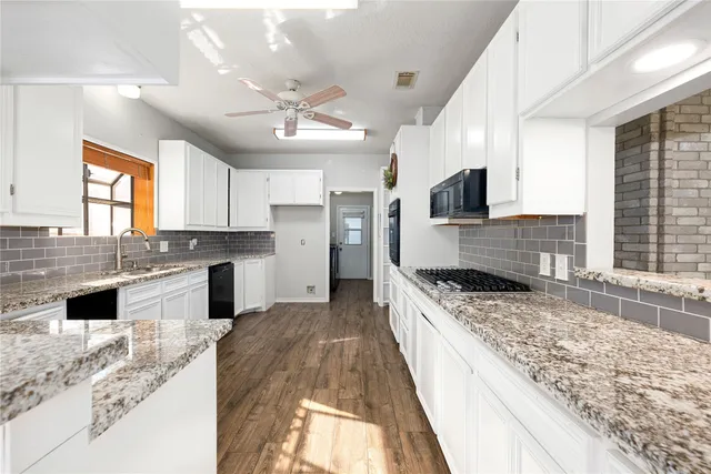 a large kitchen with granite countertop a stove top oven a sink a counter space and cabinets