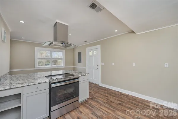 a kitchen with granite countertop stainless steel appliances a stove and a wooden floor