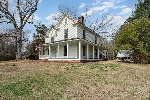 a view of a house with a yard and large tree
