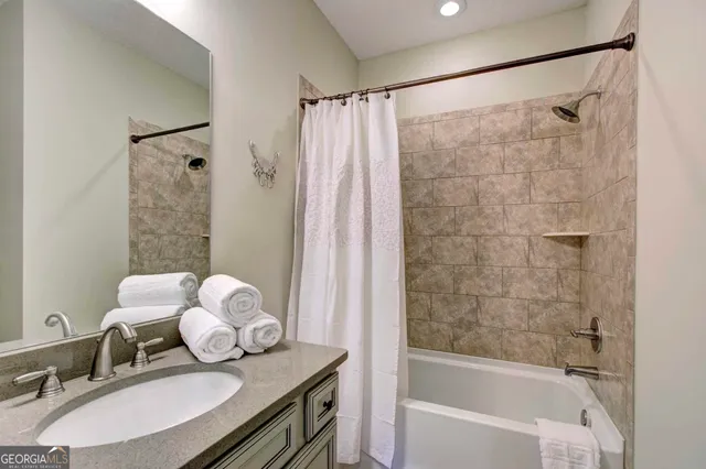 a bathroom with a granite countertop sink a mirror a bathtub and shower