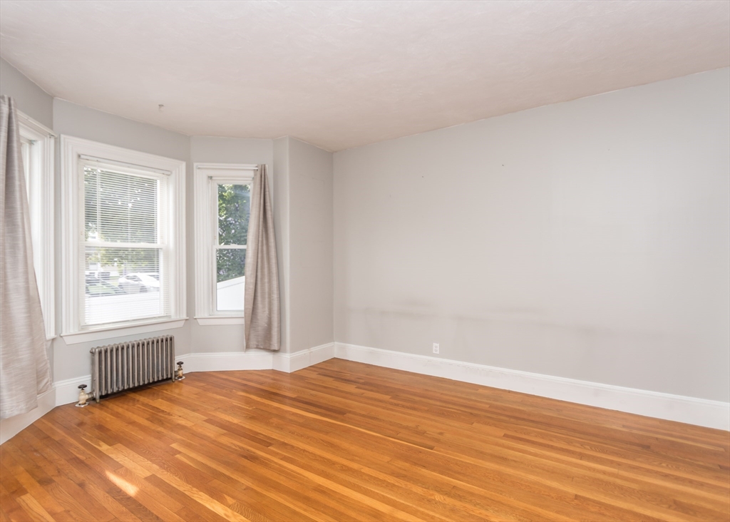 21 Gardner Street, Unit 1 Waltham, MA 02453 - Photo 8 of 19 an empty room with wooden floor and windows