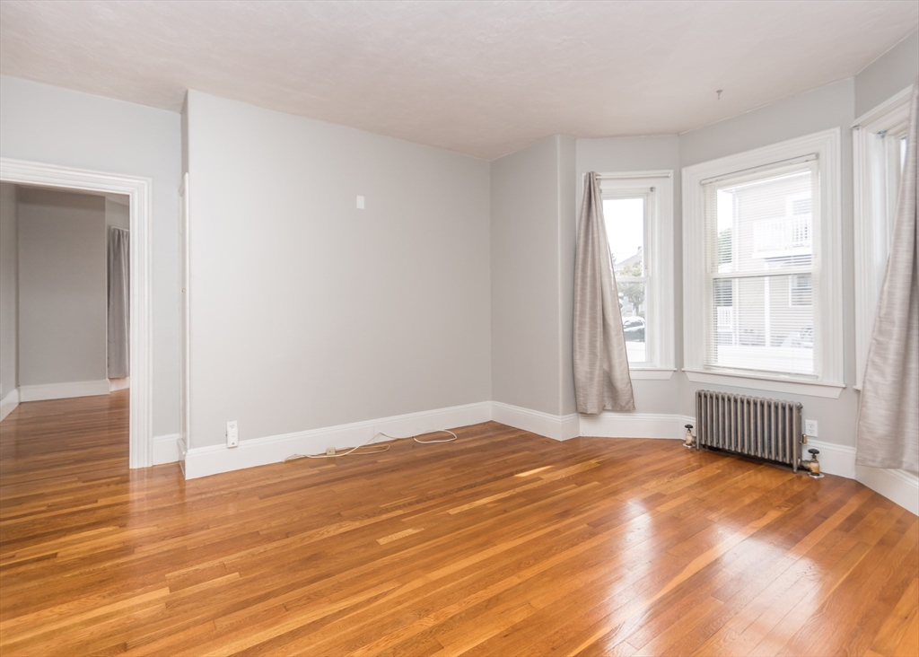 21 Gardner Street, Unit 1 Waltham, MA 02453 - Photo 9 of 19 a view of an empty room with wooden floor and a window