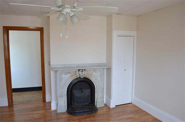 28 Washington Square Gloucester, MA 01930 - Photo 6 of 26 an empty room with a fireplace and wooden floor