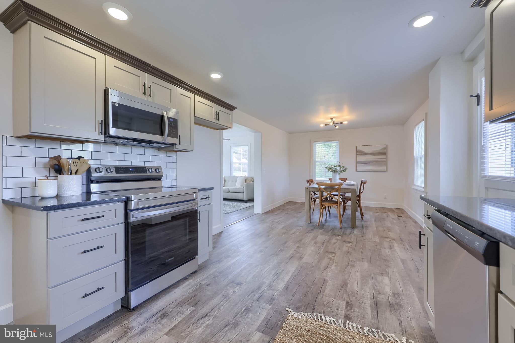 1151 Delta Road Red Lion, PA 17356 - Photo 17 of 44 a kitchen with stainless steel appliances granite countertop a stove top oven a sink a dining table and chairs with wooden floor