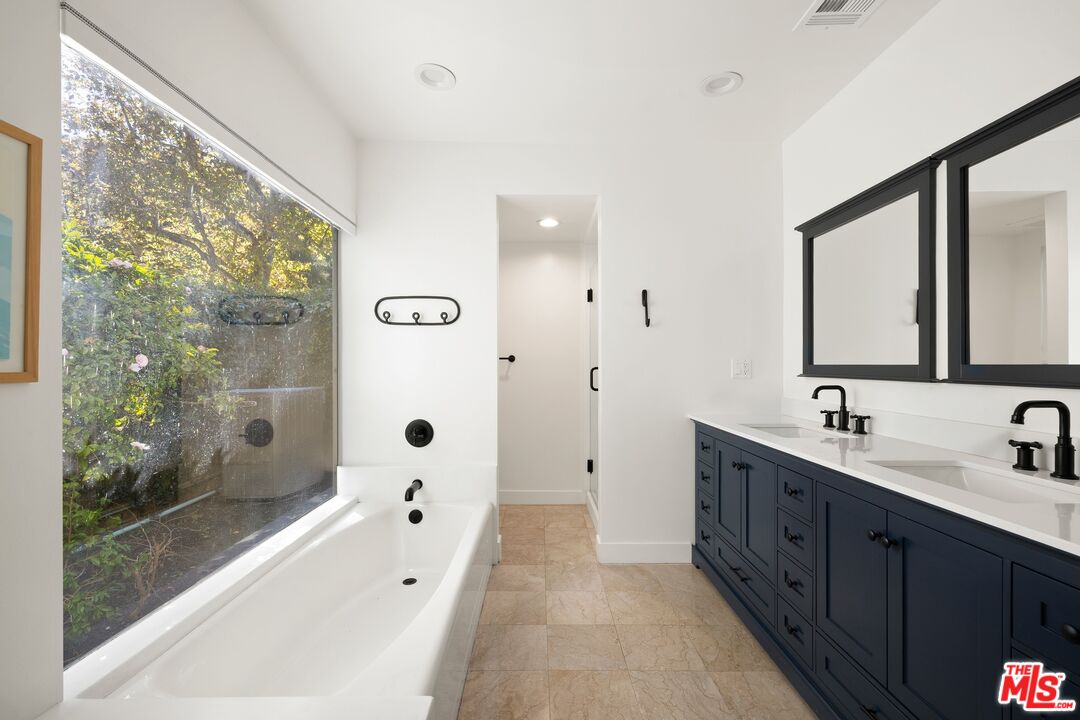 1456 Roscomare Road Los Angeles, CA 90077 - Photo 14 of 21 a spacious bathroom with a double vanity sink a large mirror a bathtub and shower
