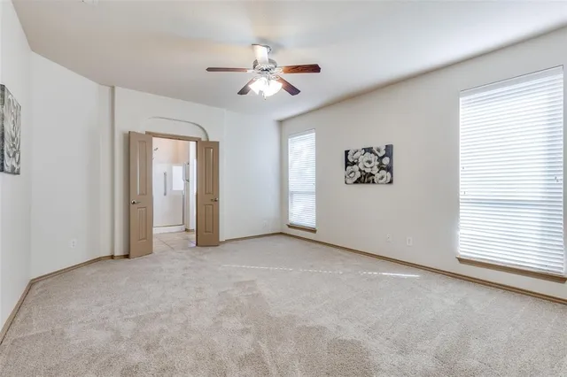 an empty room with windows and fan