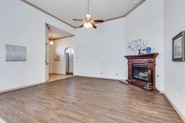 a view of an empty room with wooden floor fireplace and a window