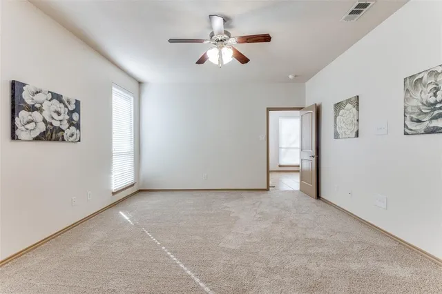 an empty room with windows and fan