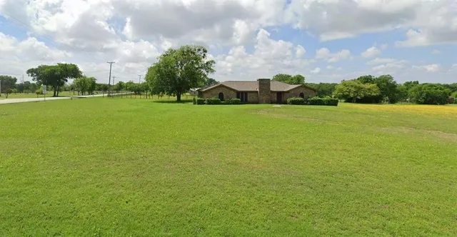 a view of a green field with house in the background