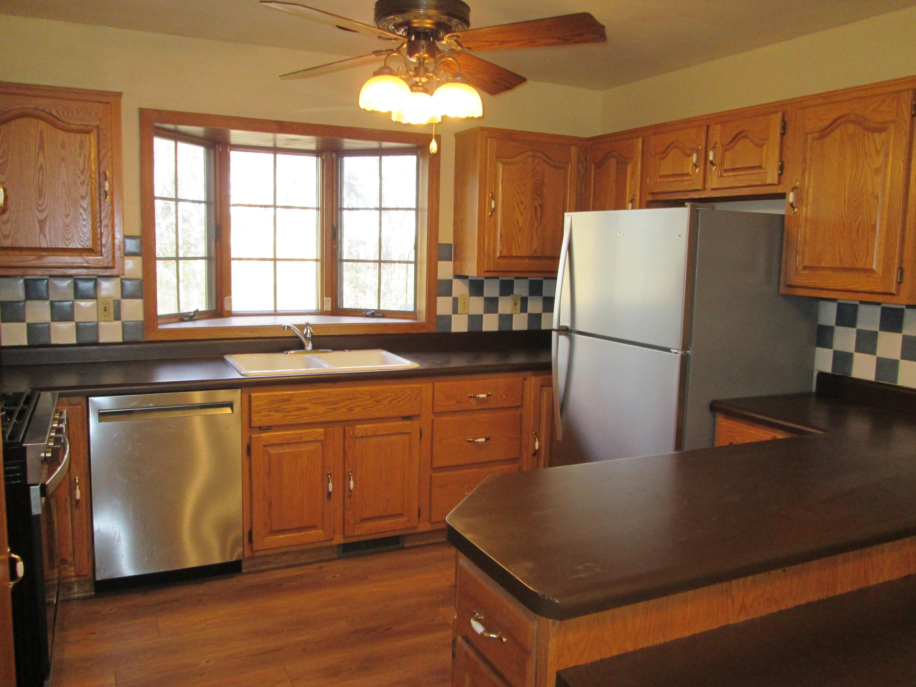 23900 Cline Avenue Lowell, IN 46356 - Photo 6 of 12 a kitchen with stainless steel appliances granite countertop a refrigerator a sink dishwasher a stove and white countertops with wooden floor