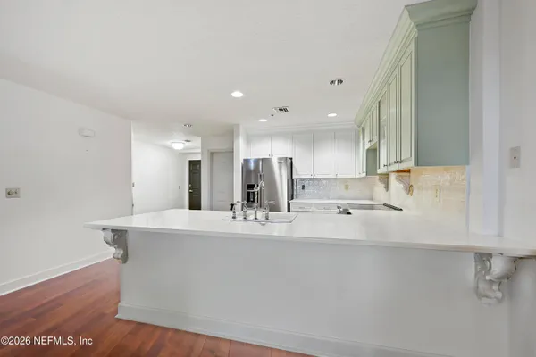 a room with kitchen island a sink and a large mirror with wooden floor