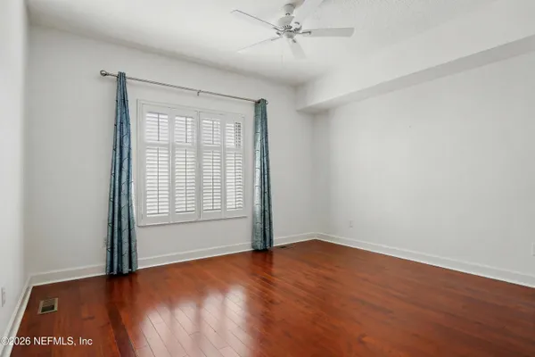 an empty room with wooden floor fan and windows