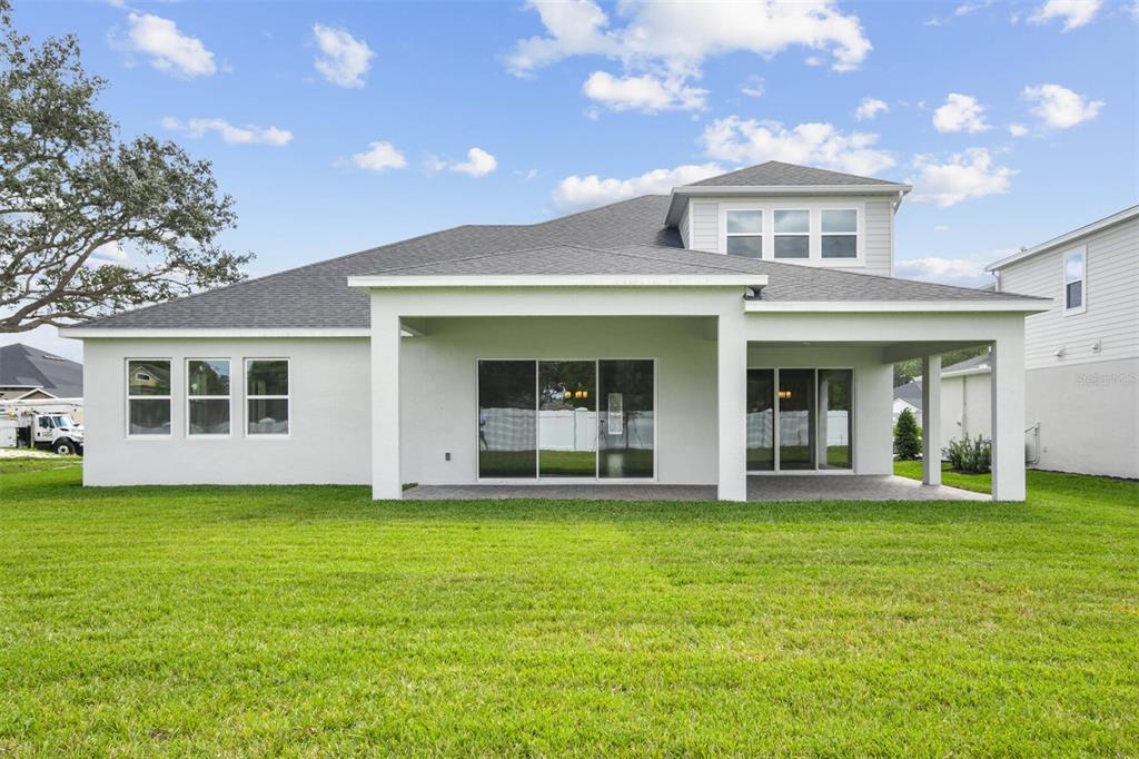17019 Overstory Road Orlando, FL 32820 - Photo 63 of 85 a view of a white house with a large windows and a yard with plants and large trees