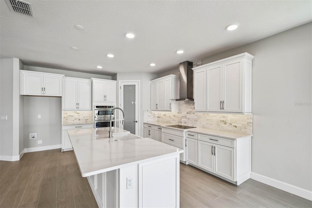 17019 Overstory Road Orlando, FL 32820 - Photo 8 of 85 a kitchen with stainless steel appliances kitchen island granite countertop a stove a sink a refrigerator and white cabinets with wooden floor