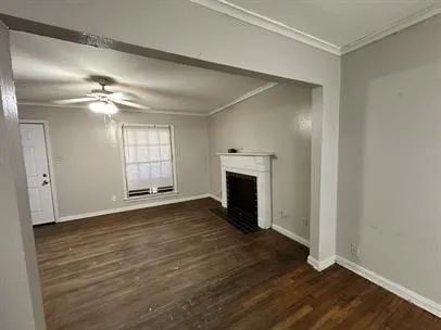 an empty room with wooden floor fireplace and windows
