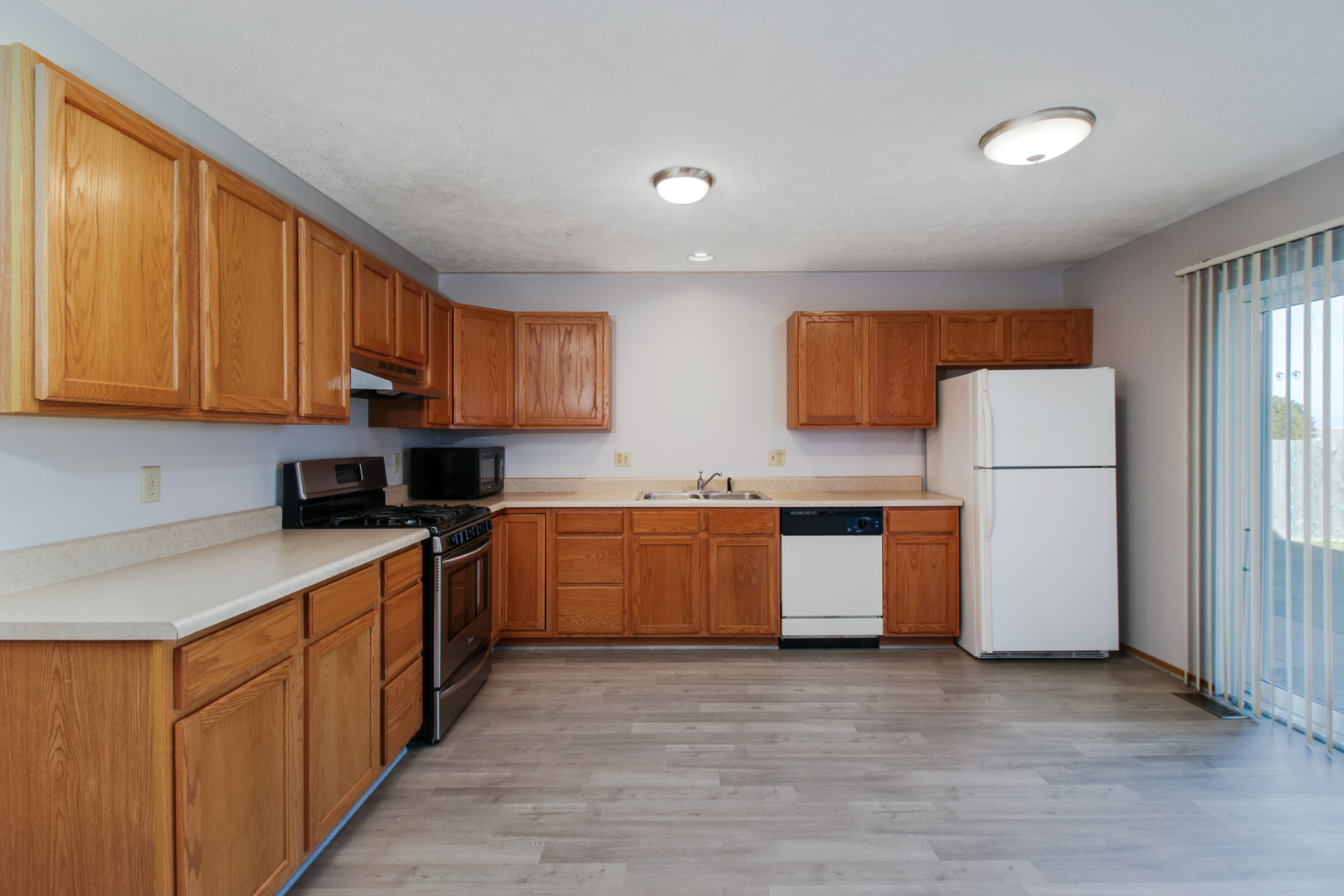 2 Andy Court, Unit 3 Bloomington, IL 61704 - Photo 7 of 28 a kitchen with stainless steel appliances granite countertop a stove top oven a refrigerator a sink and dishwasher with wooden floor