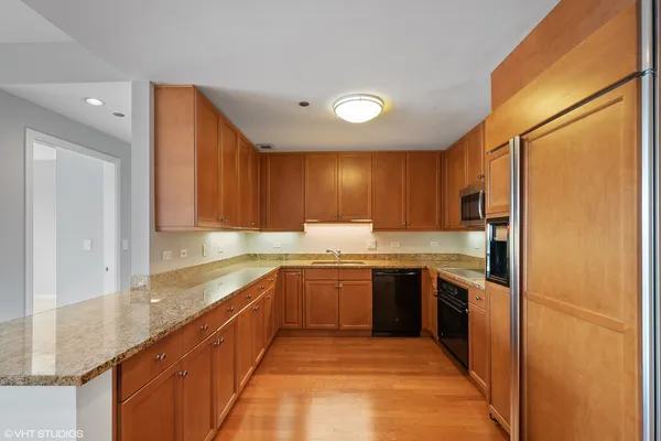 a large kitchen with stainless steel appliances granite countertop a sink and dishwasher a refrigerator with wooden cabinets