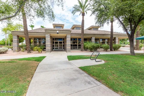 a front view of a building with garden and trees