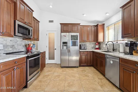 a kitchen with stainless steel appliances granite countertop a refrigerator stove and sink