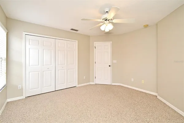 an empty room with a chandelier fan and windows