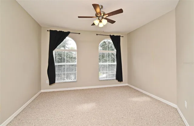 an empty room with windows and chandelier fan
