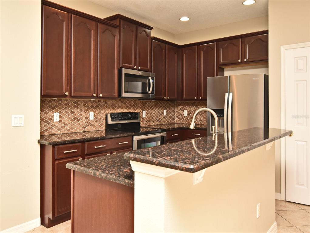 5072 Cypress Branch Point Oviedo, FL 32765 - Photo 6 of 23 a kitchen with wooden cabinets a microwave and refrigerator