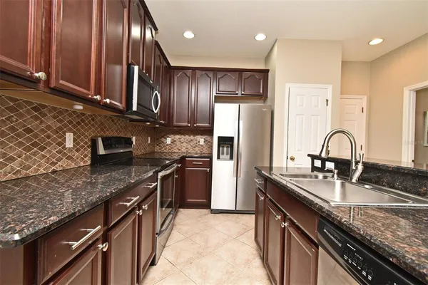 a kitchen with stainless steel appliances granite countertop a sink a stove and a refrigerator