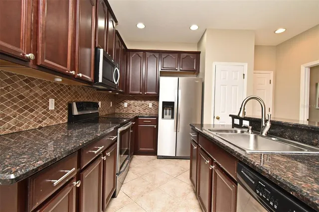 a kitchen with stainless steel appliances granite countertop a sink a stove and a refrigerator