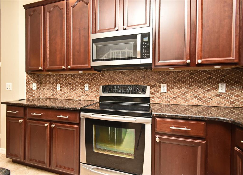 5072 Cypress Branch Point Oviedo, FL 32765 - Photo 9 of 23 a kitchen with granite countertop cabinets stainless steel appliances and wooden cabinets