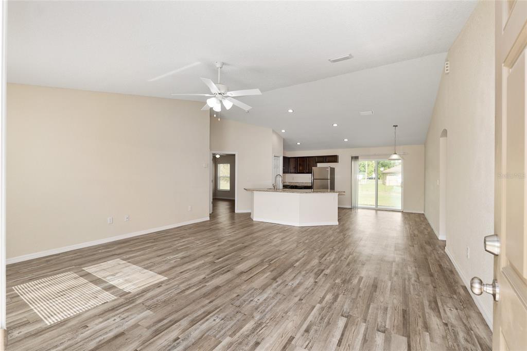 22 Juniper Loop Circle Ocala, FL 34480 - Photo 13 of 53 a view of empty room with wooden floor and kitchen view