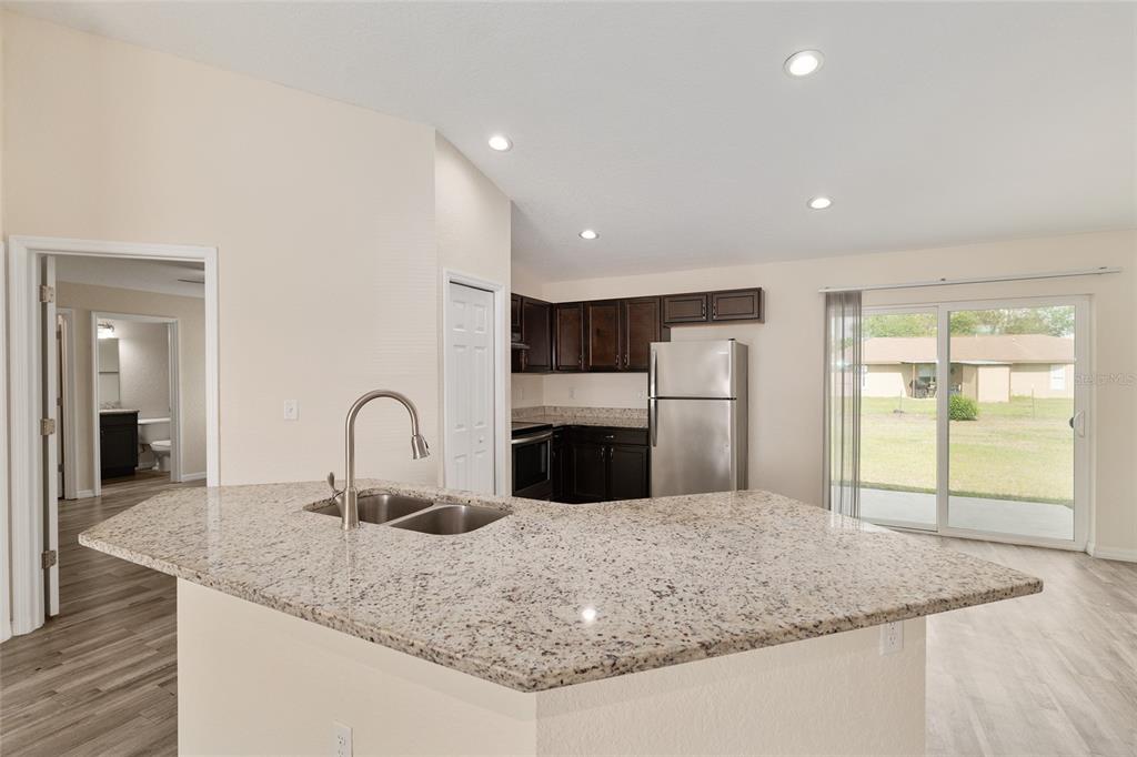 22 Juniper Loop Circle Ocala, FL 34480 - Photo 24 of 53 a kitchen with stainless steel appliances granite countertop a sink a stove and a refrigerator