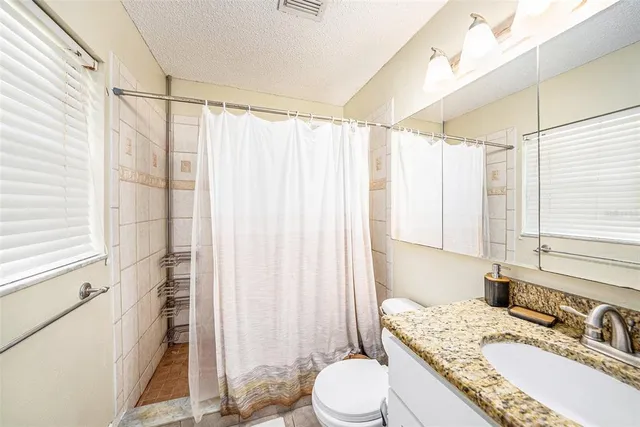 a bathroom with a granite countertop sink toilet and shower