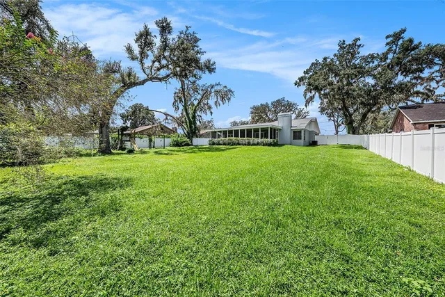 a view of a house with a big yard and large trees