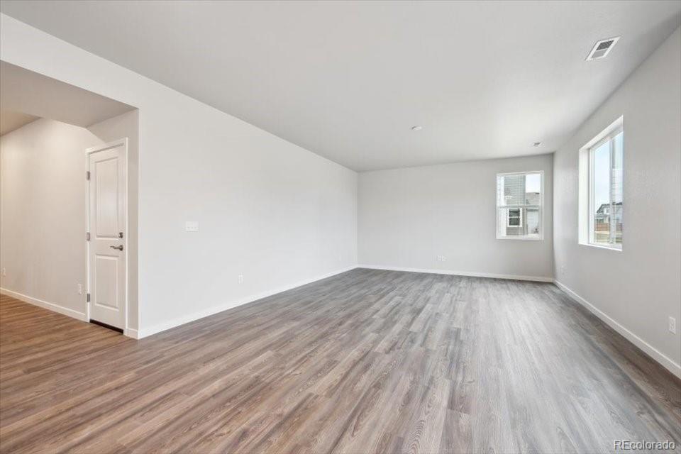 1382 Farmstead Street Brighton, CO 80601 - Photo 7 of 22 a view of an empty room with wooden floor and a window