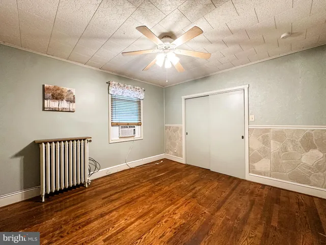 an empty room with wooden floor fan and windows