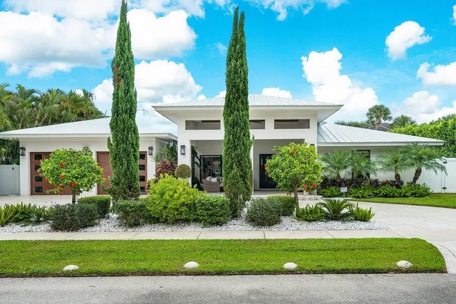 a front view of a house with a yard and potted plants