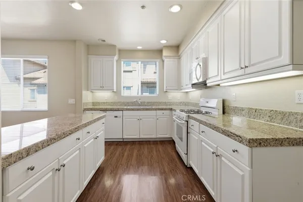 a view of a kitchen with granite countertop white cabinets and a wooden floor