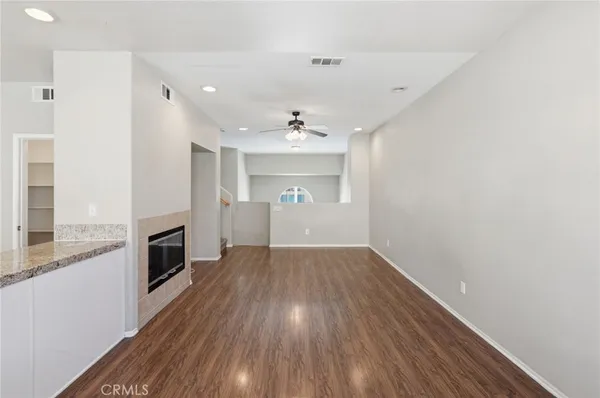 a large kitchen with granite countertop a stove top oven a sink and white cabinets with wooden floor