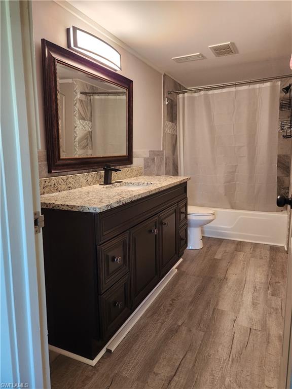 7141 Dell Road, Unit 3 New Port Richey, FL 34653 - Photo 8 of 12 a bathroom with a granite countertop sink a toilet a mirror and shower curtain