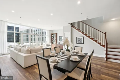a dining room with wooden floor windows and a kitchen view