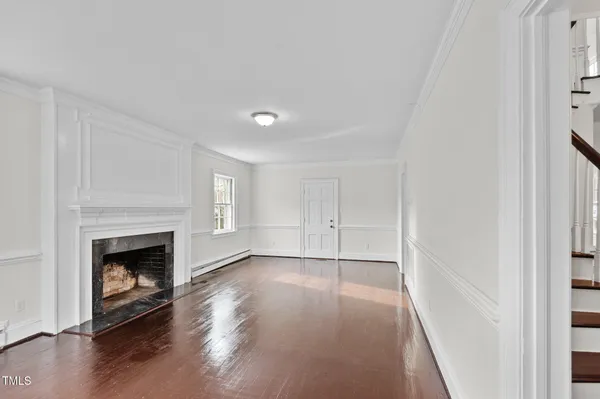 a view of empty room with wooden floor and fireplace