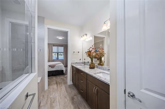 a en suite bathroom with a granite countertop double vanity sink a mirror and a shower