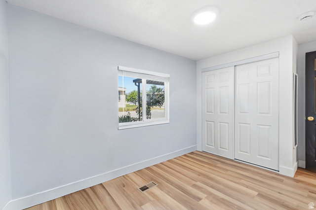 2500 North Fort Lane, Unit 220 Layton, UT 84041 - Photo 18 of 23 Room featuring wood-finish flooring, a window with a roller shade, and white paneled sliding closet doors