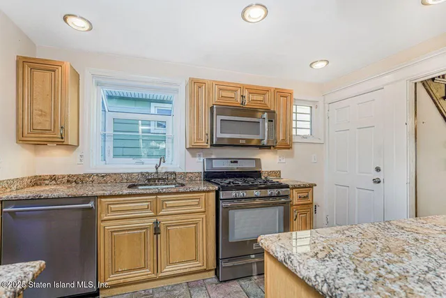 a kitchen with stainless steel appliances granite countertop a stove a sink and a microwave
