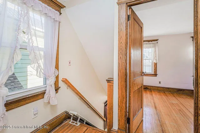 a view of a hallway with wooden floor and a living room